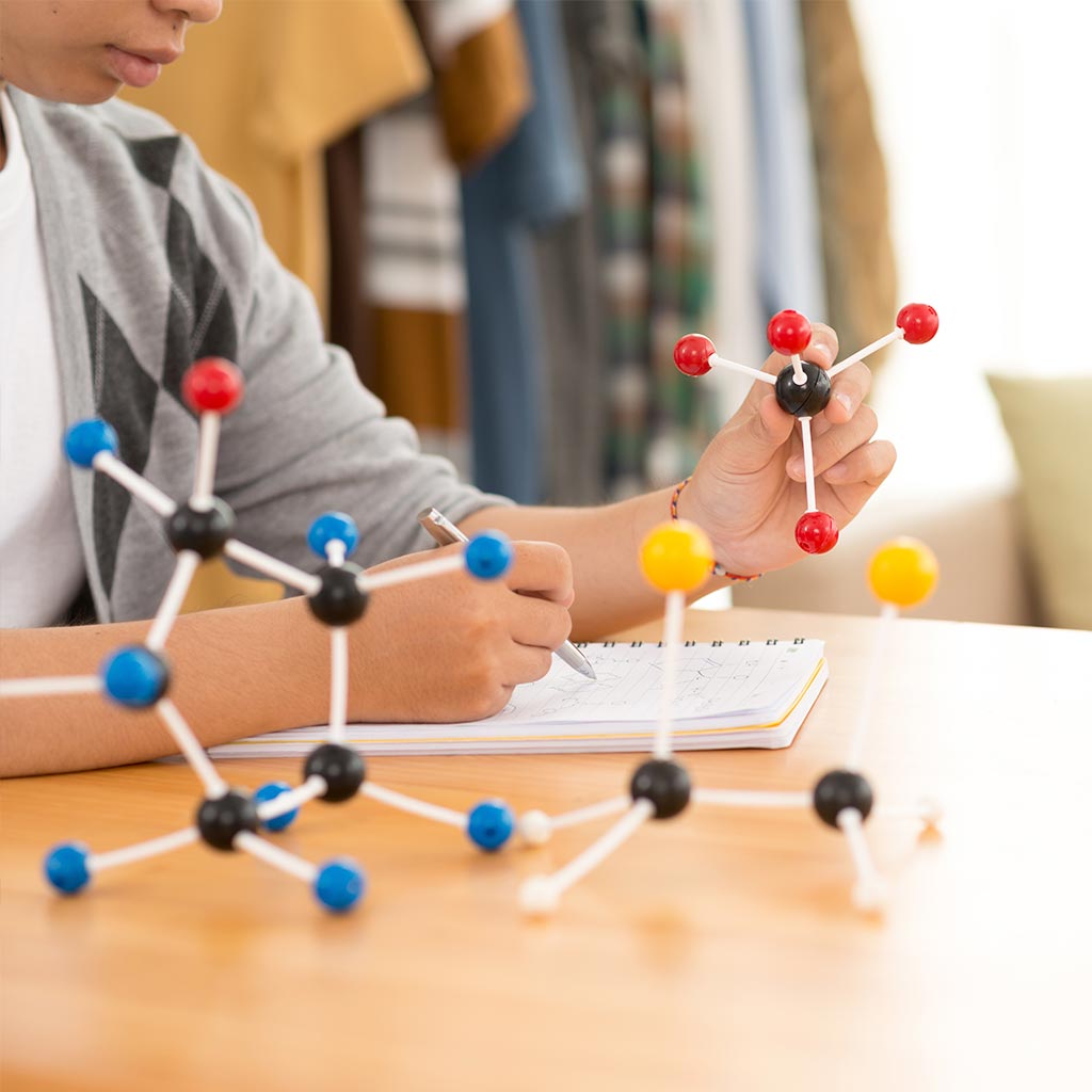 Un alumno examinando ejemplos de química hechos con figuras.